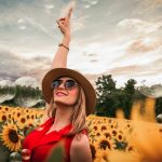 woman surrounded by sunflowers raising hand 1261459