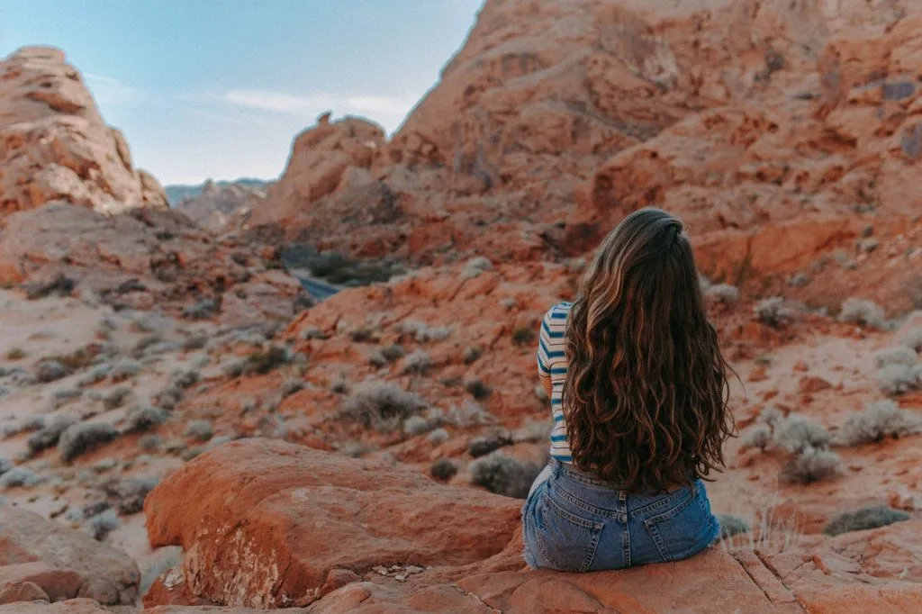 woman in blue denim shorts sitting on brown rock mountain 3935704 scaled